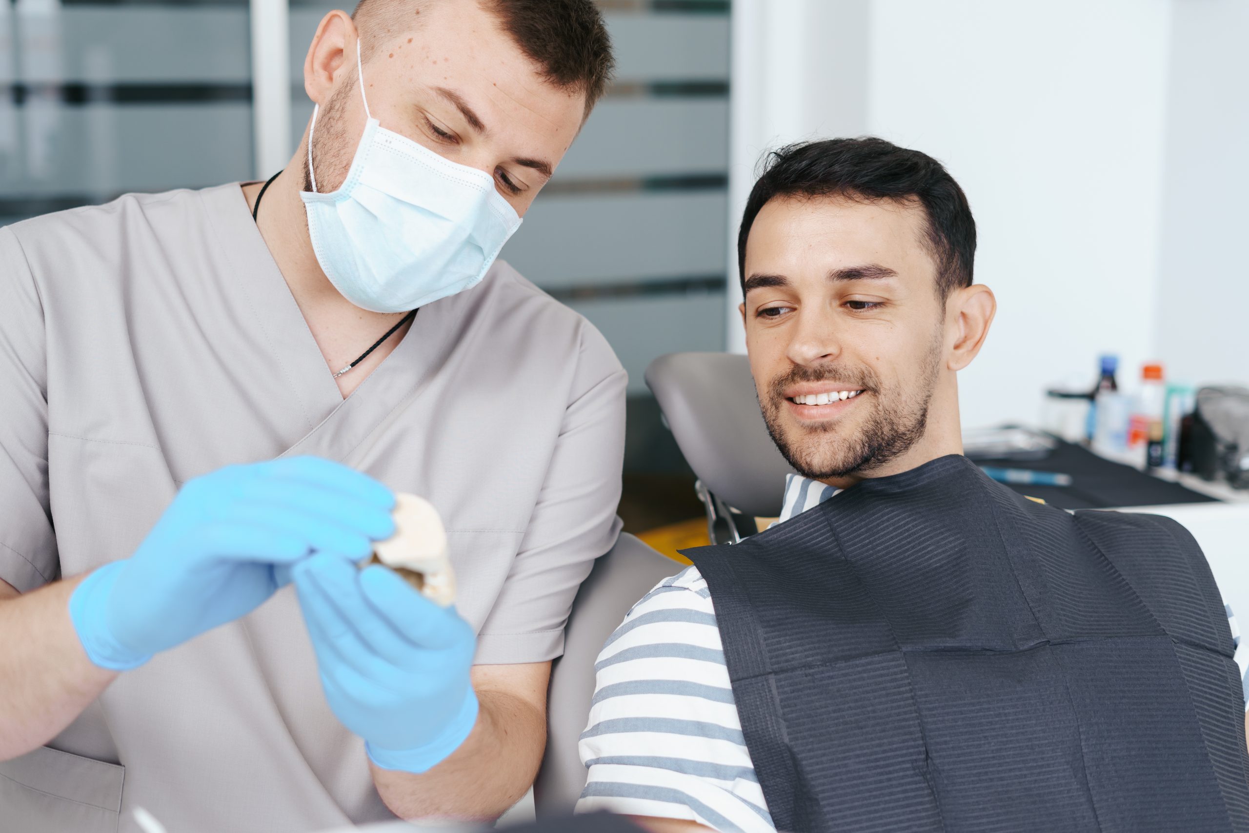 Male Dentist Showing Patient The Artificial Dentures